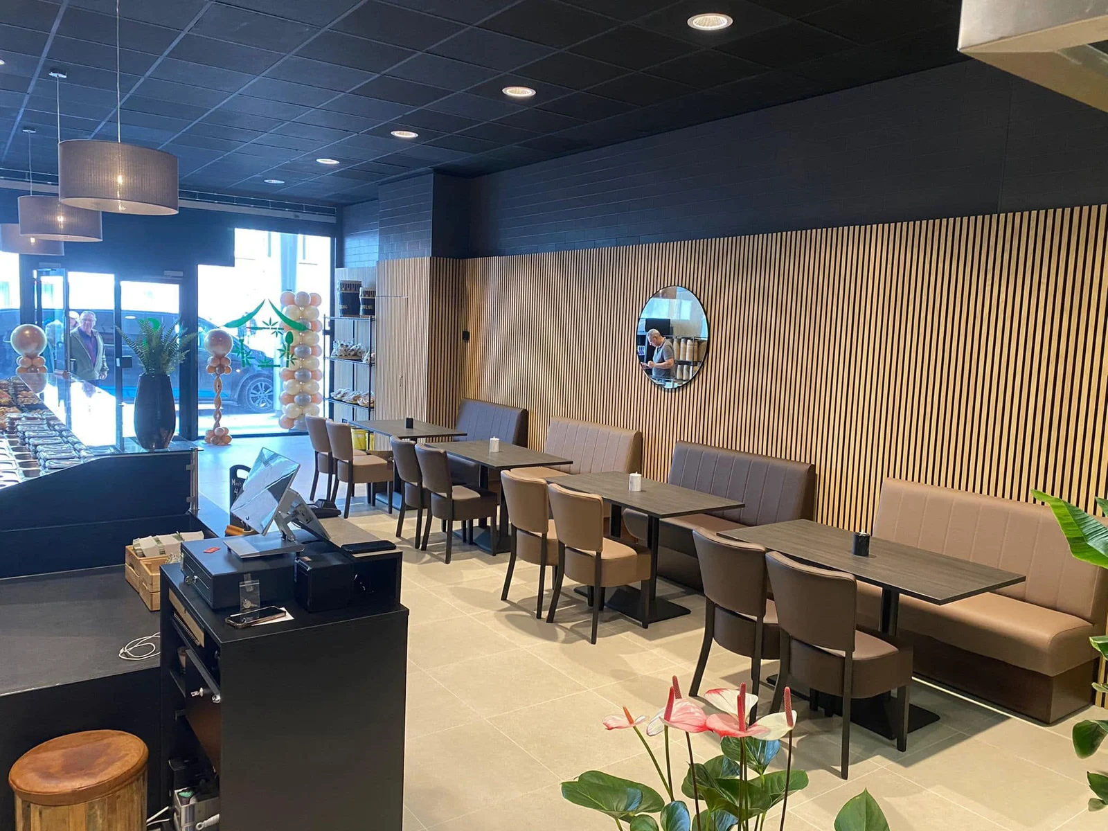 Een restaurantzaal met houten lamellen en zitbanken, verbouwd door ADV BOUW.