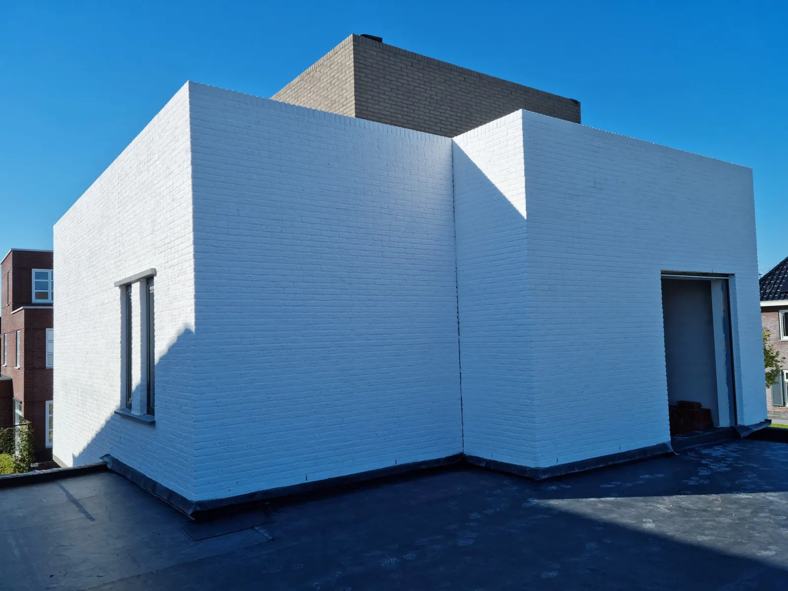 Een nieuwe woning met witte gevelsteen en een strak plat dak in Middelburg.