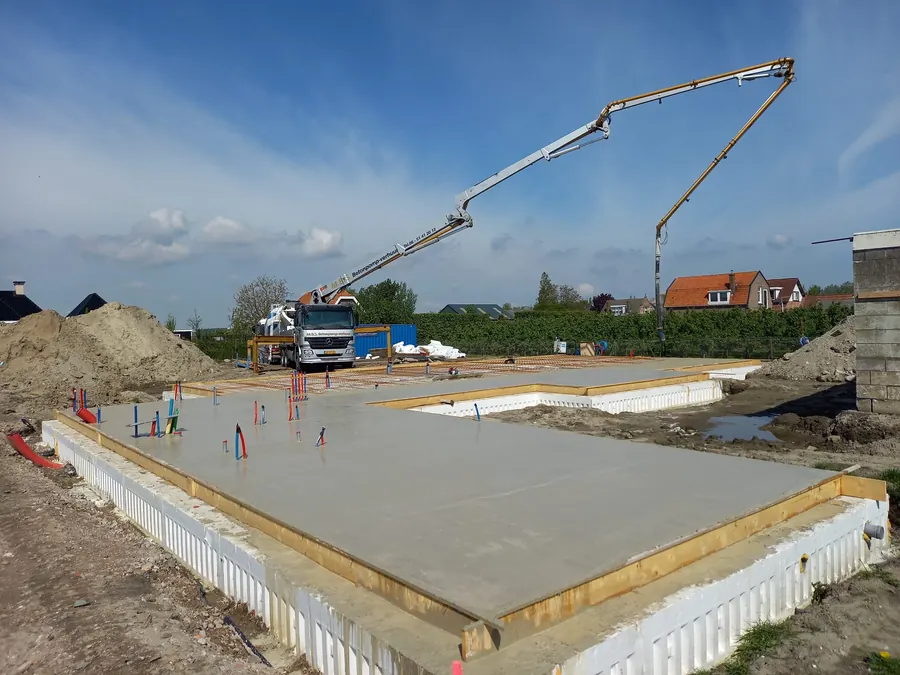 Een betonpomp stort de vloer van een nieuwe woning in de bekisting.