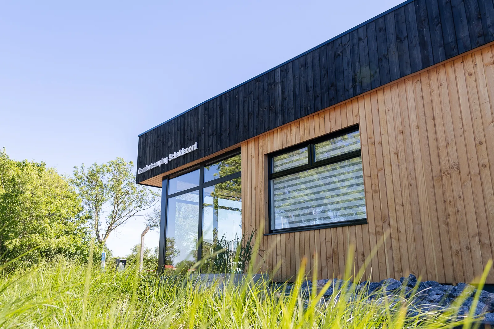 Het vernieuwde gebouw van vakantiepark Scheldeoord met een gevel van zwart en licht hout.